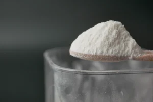 Natron auf einem Löffel über einem Glas zum Zähne mit Natron putzen