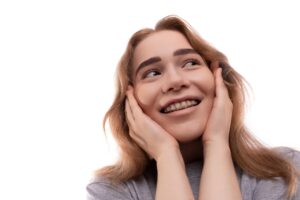 Modest teenage girl with blond hair and braces on a white background