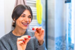 Woman in the bathroom putting on transparent braces