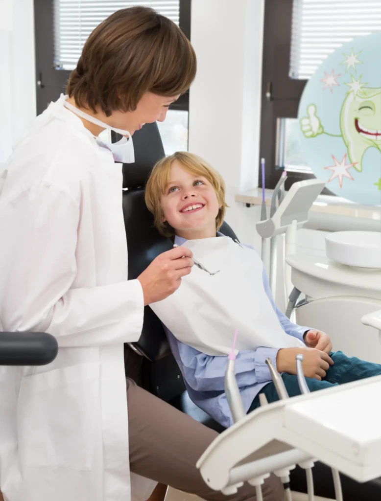 Kind beim Zahnarztbesuch lächelt im Behandlungsstuhl