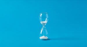 Sanduhr mit weißem Sand auf blauem Hintergrund