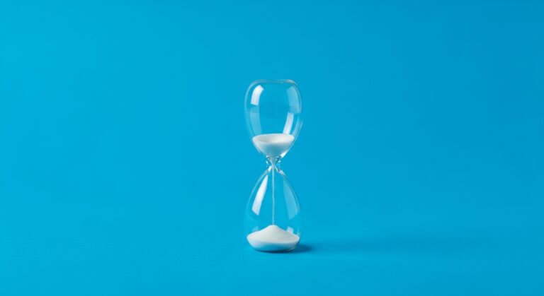 Sanduhr mit weißem Sand auf blauem Hintergrund