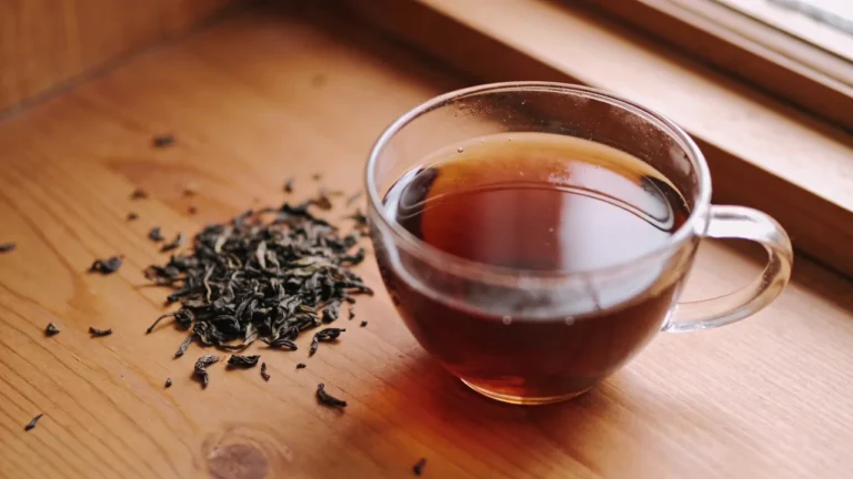 Glas Tasse mit schwarzem Tee auf Holztisch